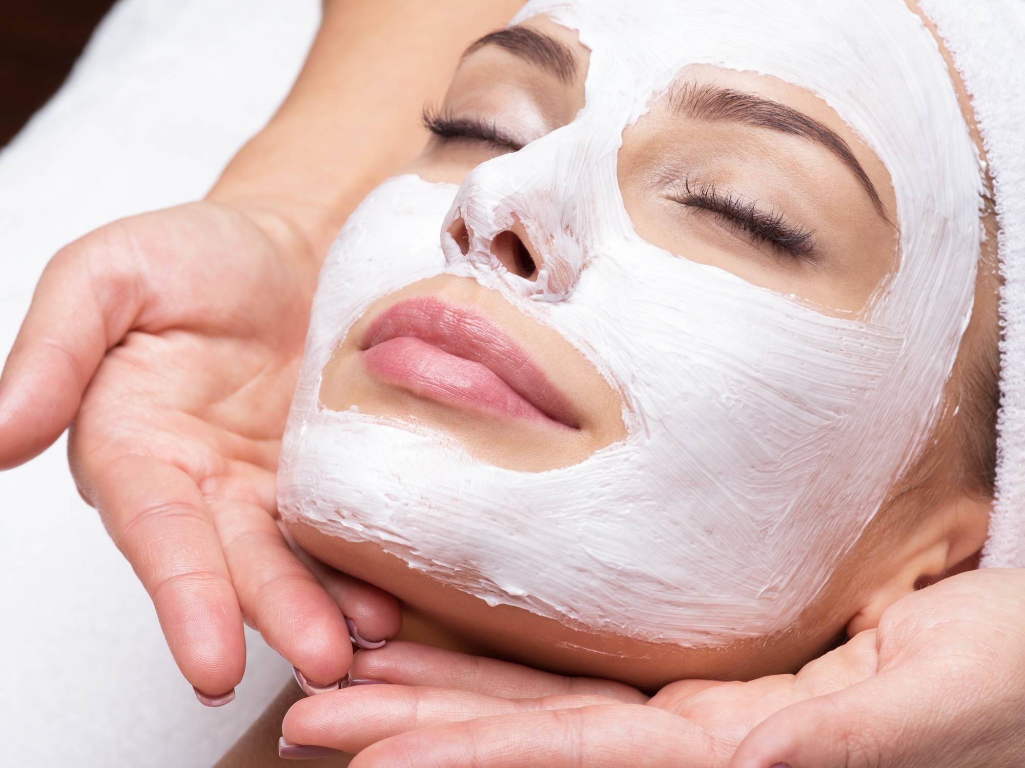Spa massage for woman with facial mask on face