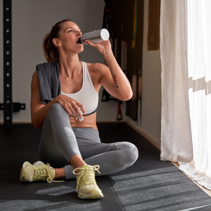 Fit woman drinking water after training