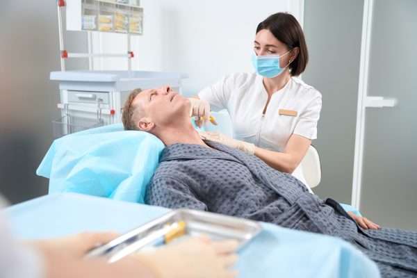 Professional medic injecting platelet rich plasma into patient neck